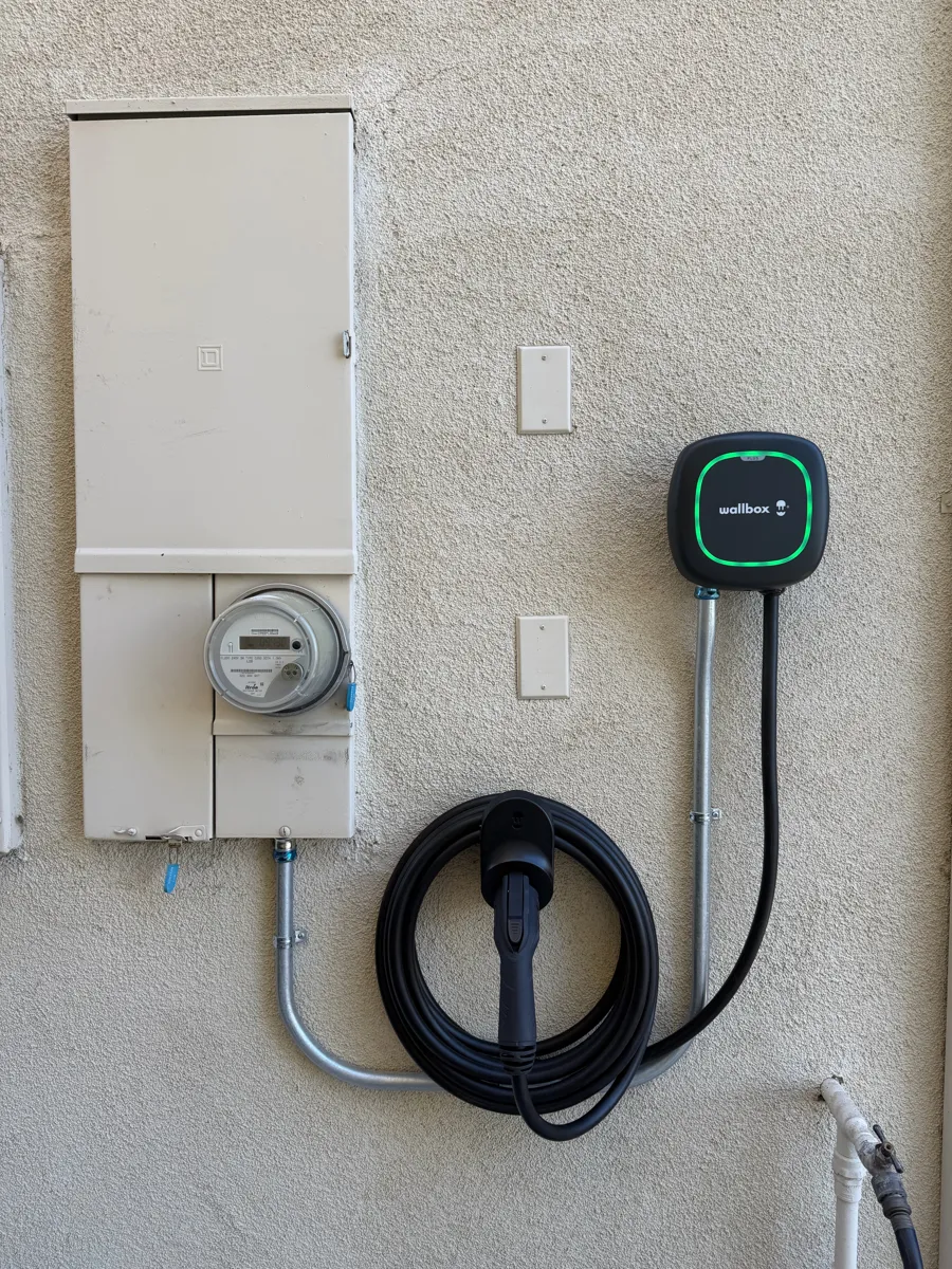 Wallbox Pulsar charger next to a meter panel with conduit, outdoors